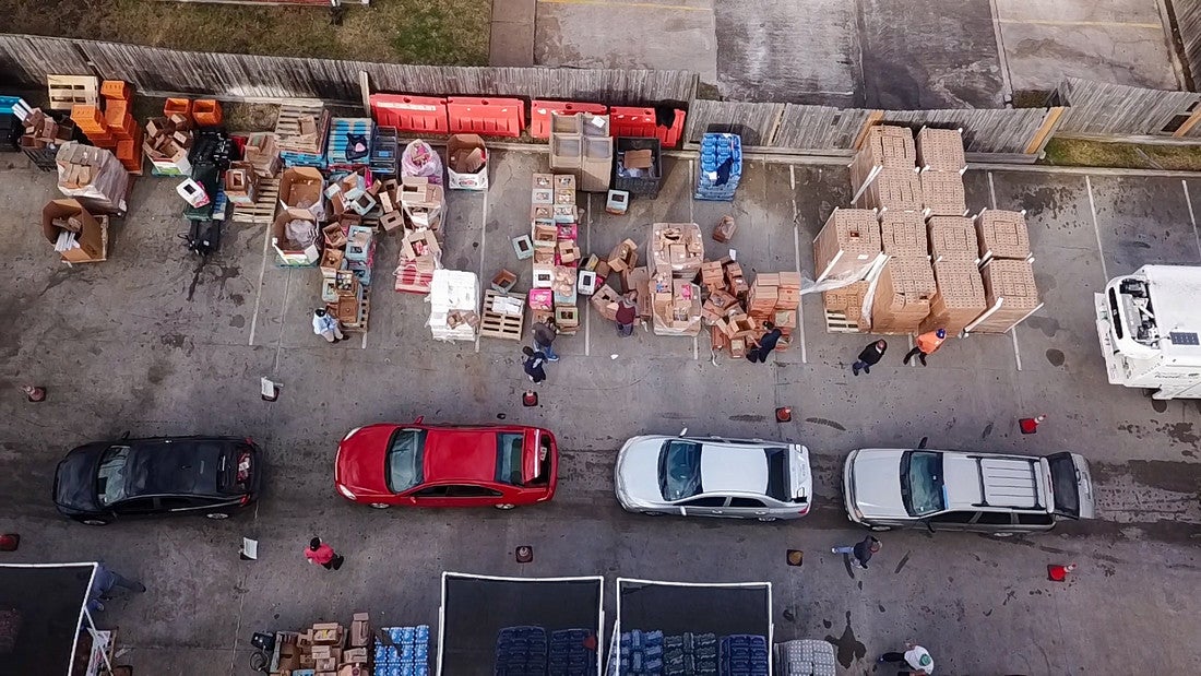 A drone shot of a line of cars in a parking lot.