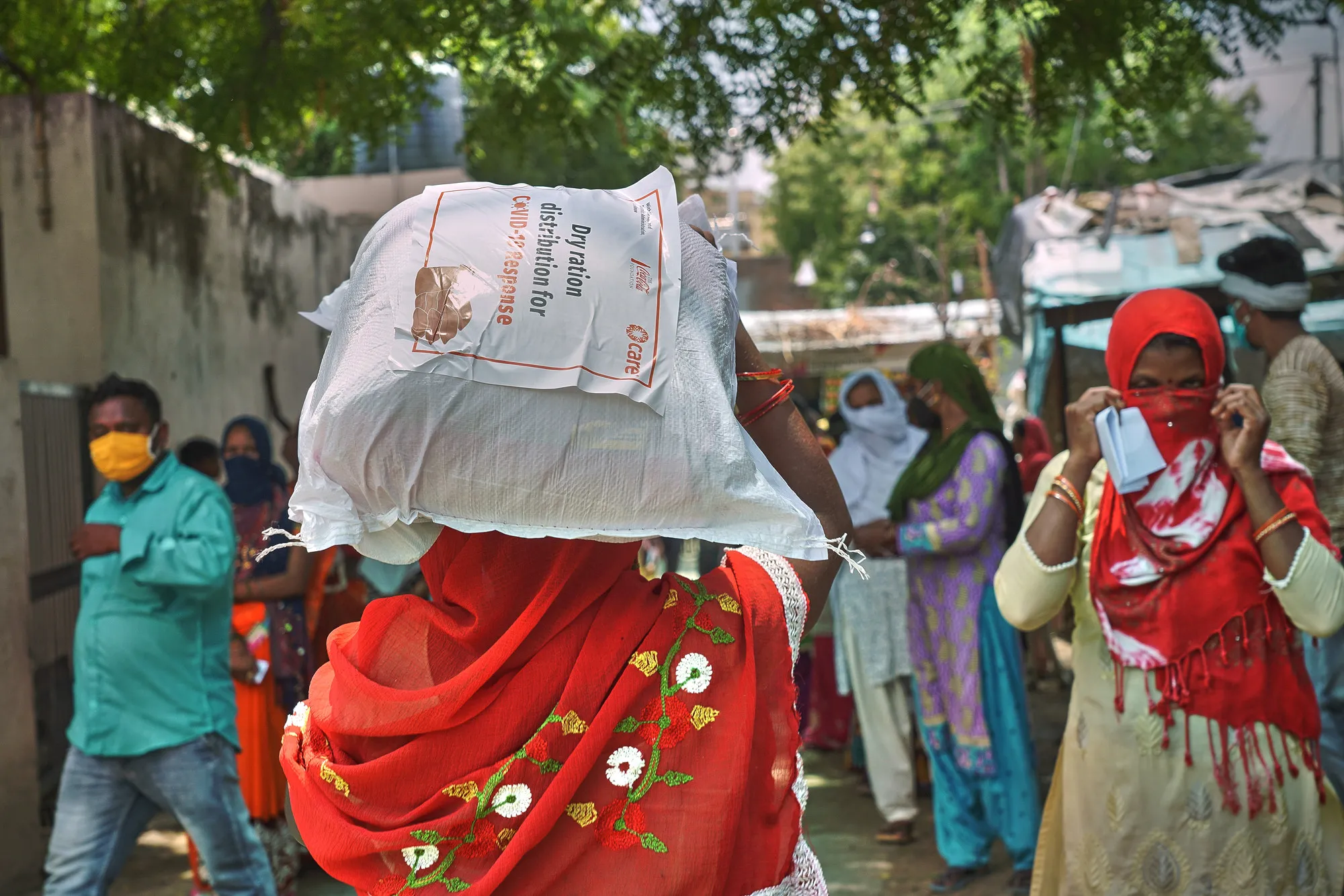 A woman carries a bag of supplies on her head.