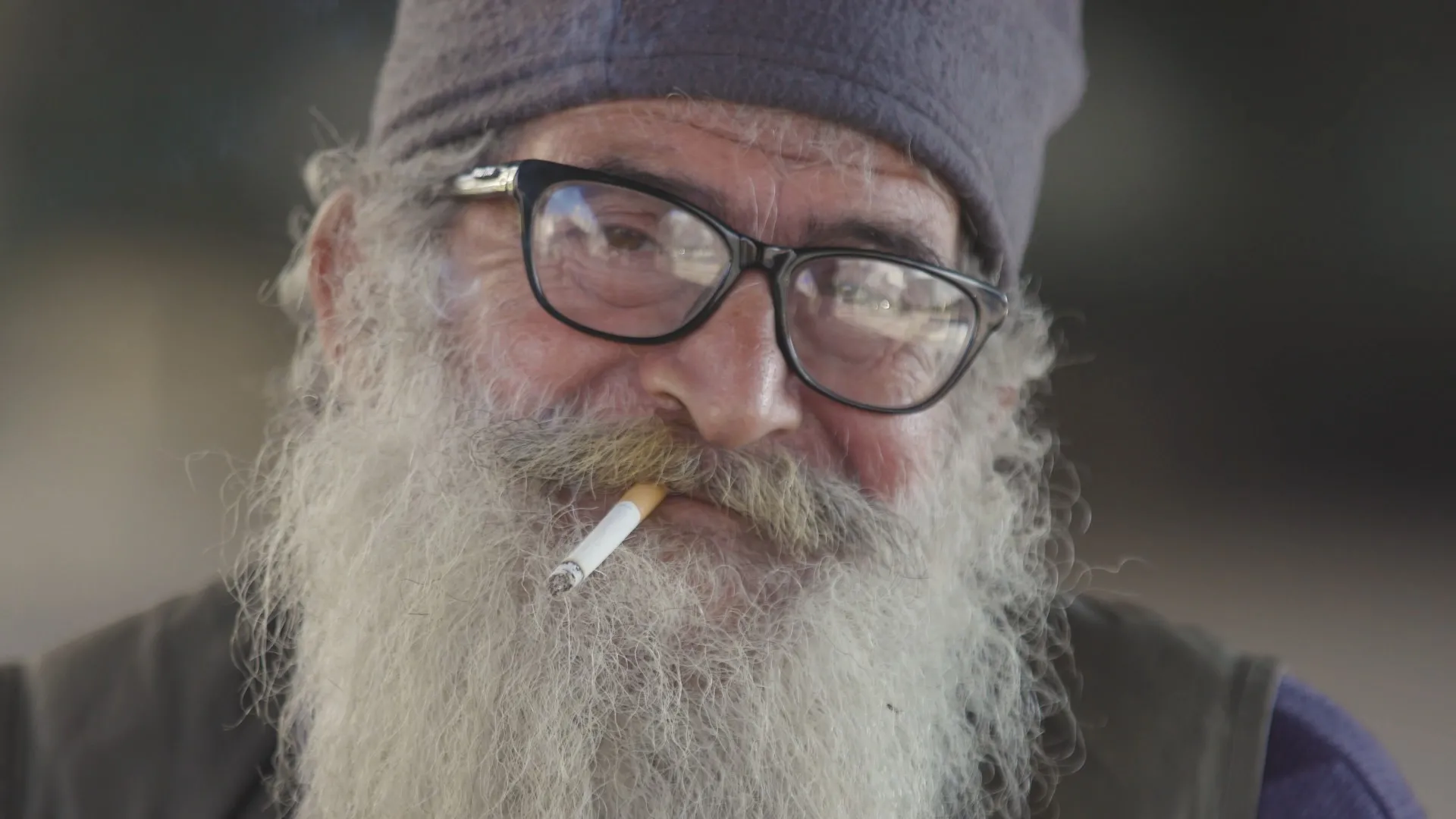 Primer plano de un anciano libanés con una espesa barba gris mientras fuma un cigarrillo