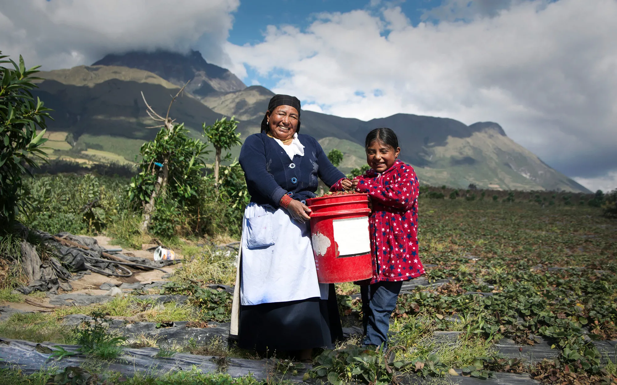 A mother and daughter stand in a field in Ecuador.