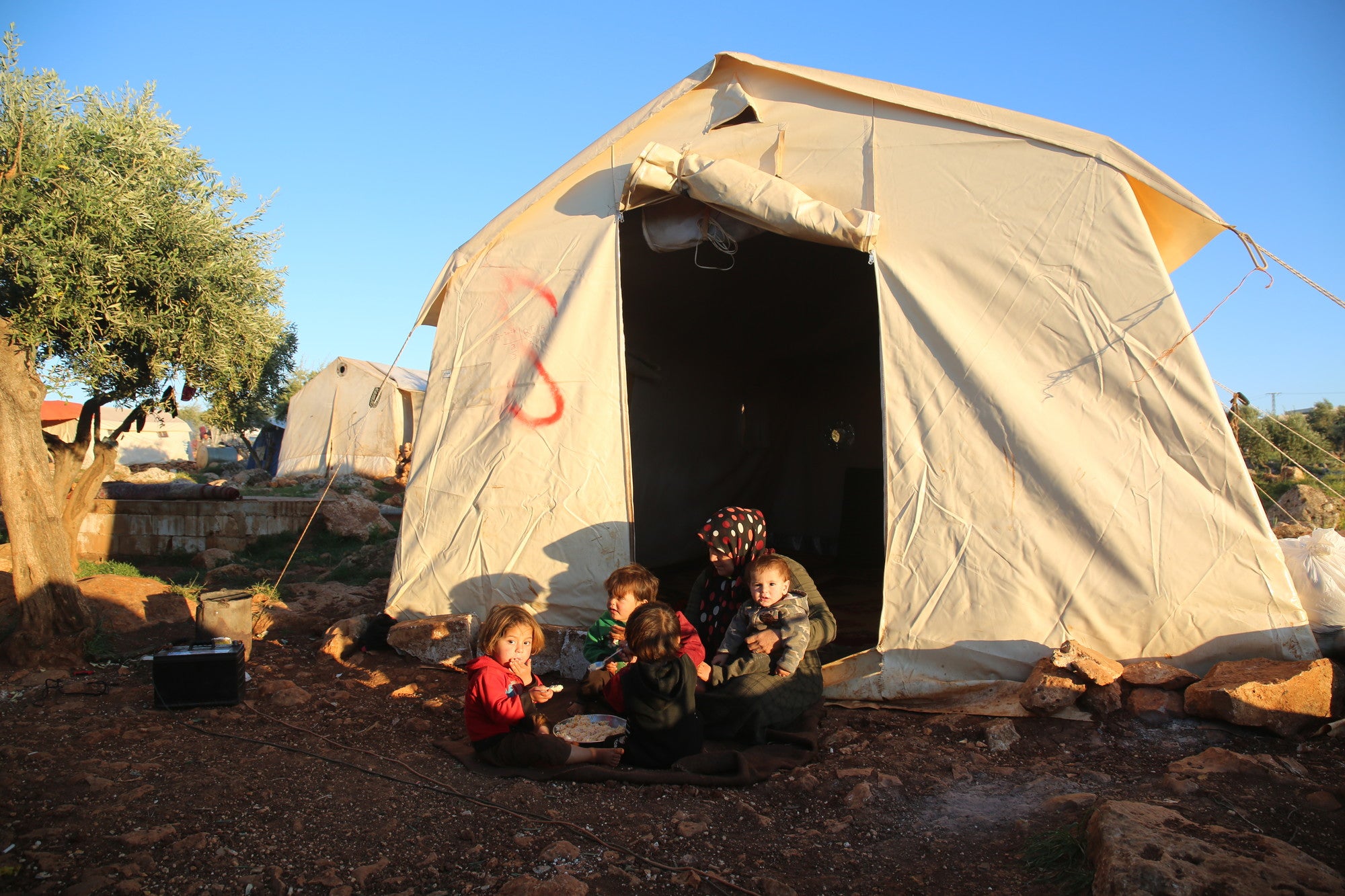 Dans un camp de déplacés à Idlib, Somaya* donne à ses petits-enfants un repas de riz devant sa tente, en attendant l'appel à la prière du coucher du soleil pour annoncer la fin du jeûne.