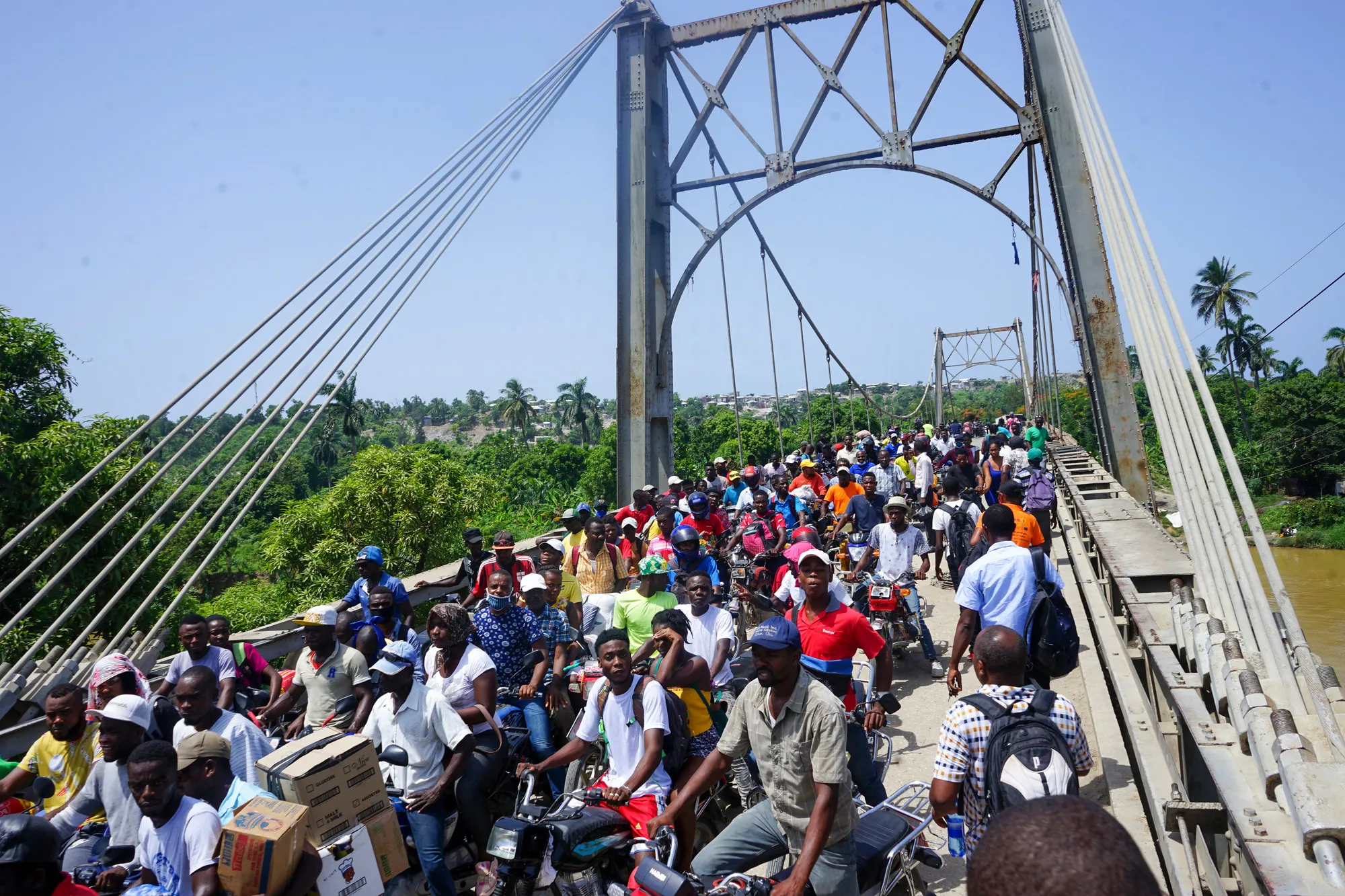 Des personnes photographiées sur et à proximité du pont Dumarsais Estimé, où les piétons et certains véhicules plus petits peuvent passer, mais pas les camions, fin août 2021, après un tremblement de terre de 7.2 qui a fait des ravages en Haïti. Le pont relie la ville de Jèrèmie au reste des autoroutes du pays.