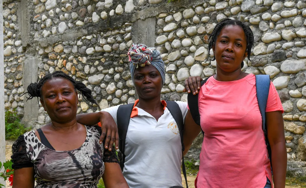 Three women stand together in Haiti.