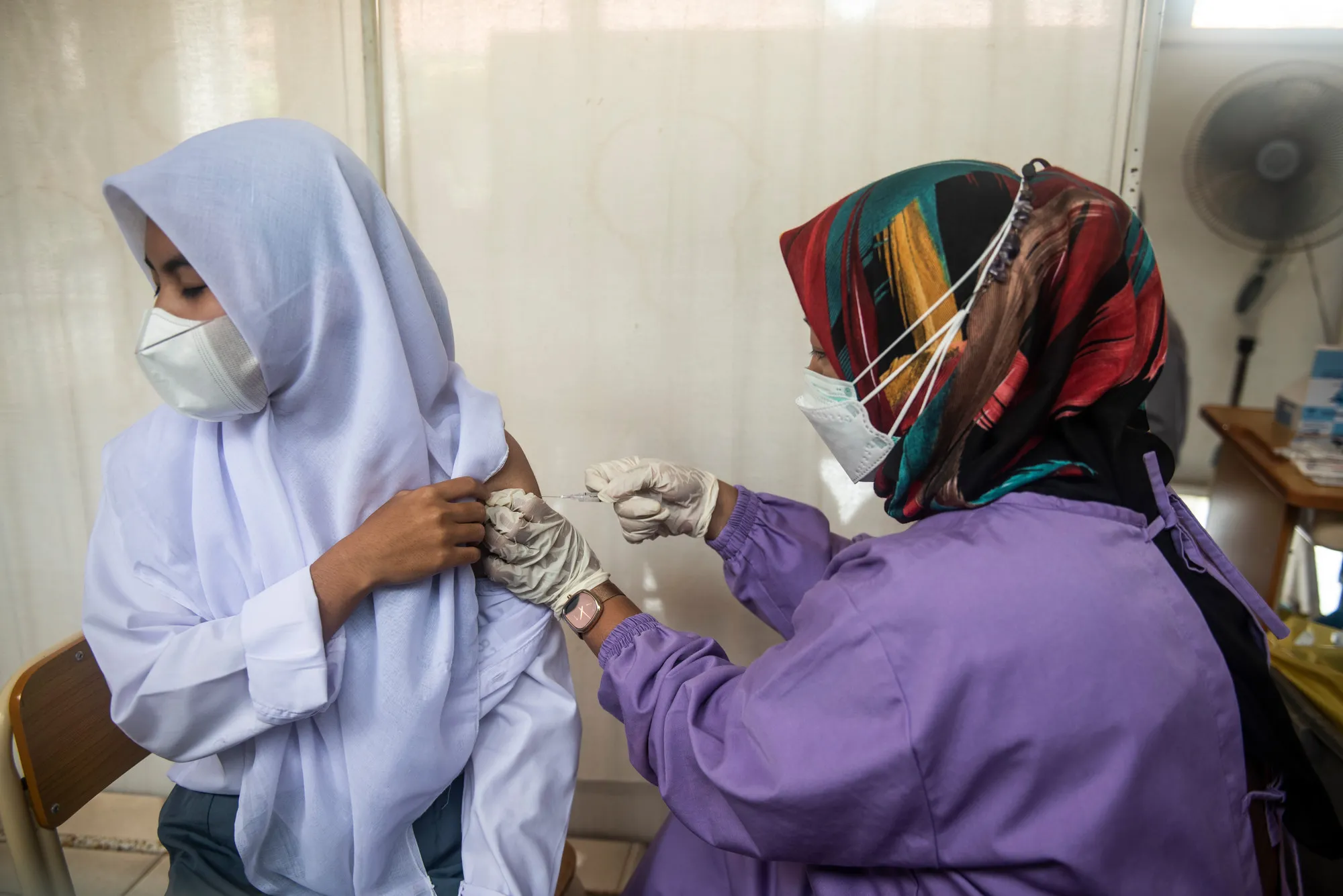 Um trabalhador de saúde injeta a vacina em alunos durante o programa de vacinação na Escola Secundária Pública Cinangka, Serang, Banten, Indonésia, segunda-feira, 9 de agosto de 2021. Os alunos precisam trazer uma carta de permissão de seus pais para serem vacinados.