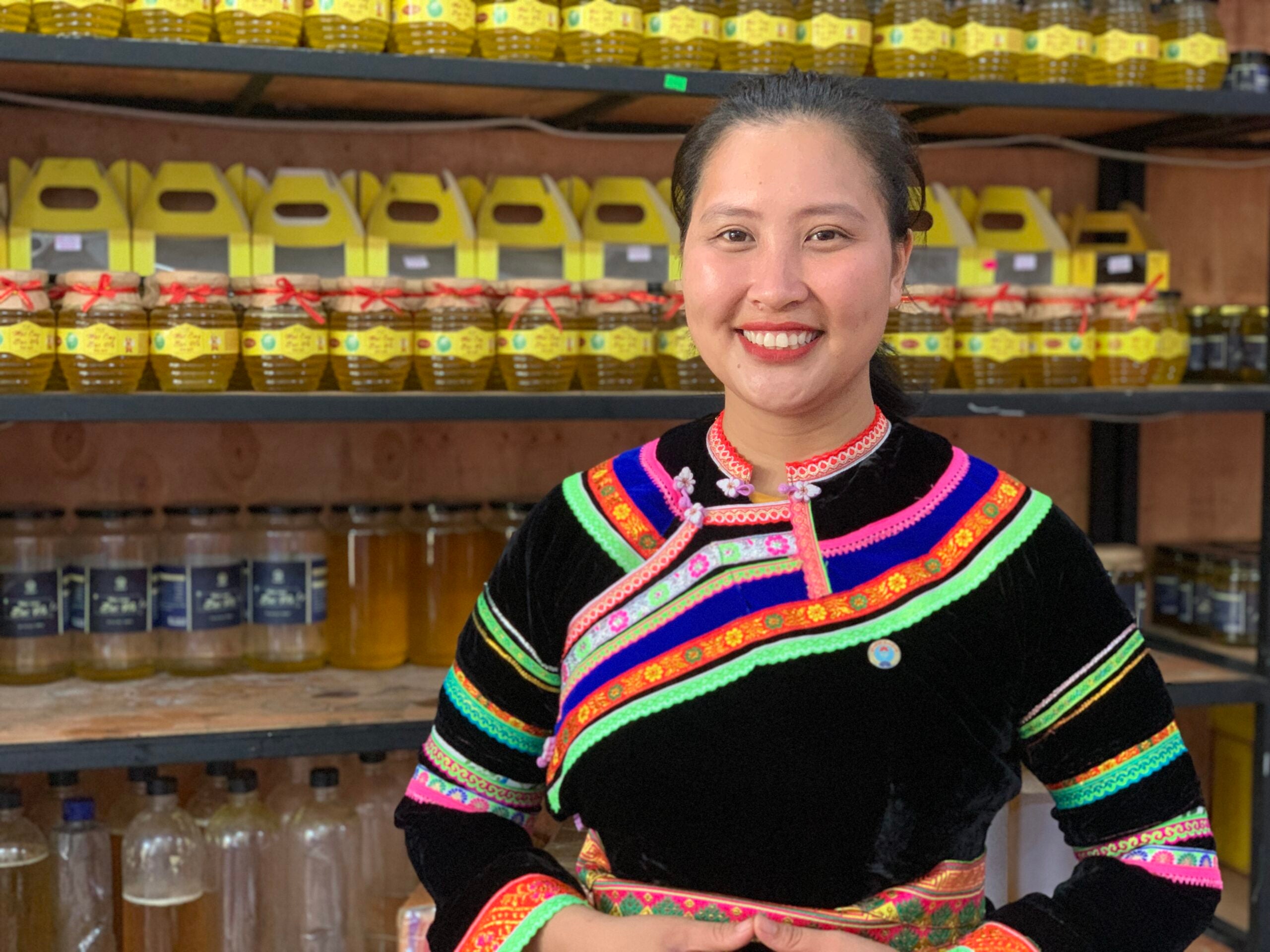 A Viet woman wearing a black shirt with colorful neon stripes stands in front of a fully stocked store shelf