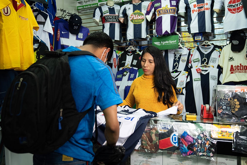 A woman helps a customer who is purchasing an athletic jersey.
