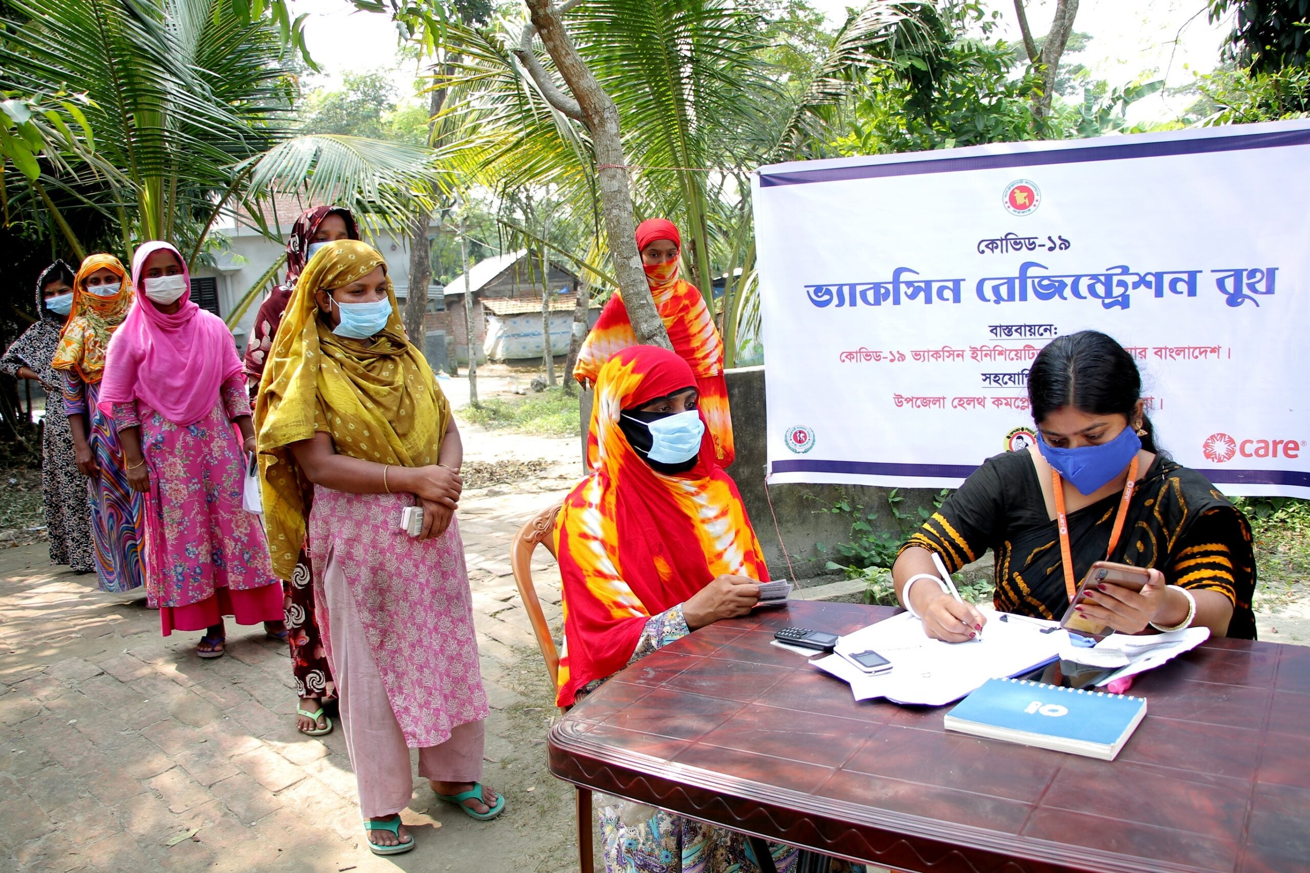 Women wait in line to get vaccinated against COVID-19 in Bangladesh