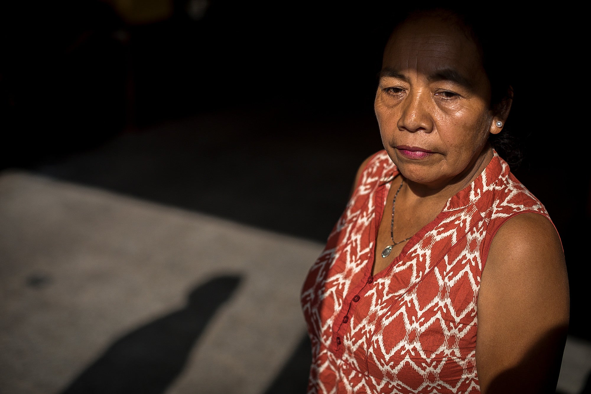 Maria Faustina was photographed in Guatemala City on April 13, 2018, as part of CARE' Domestic Workers Campaign. She looks forward in a shadowy room.