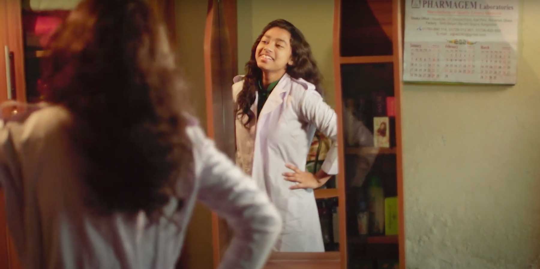 Une fille bangladaise sourit en posant devant un miroir.