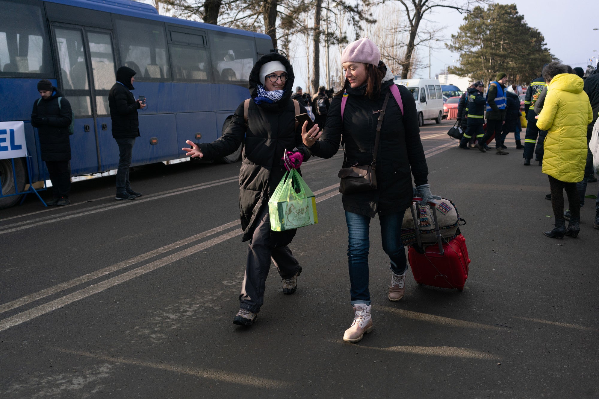 Refugiados ucranianos caminhando ao lado de um ônibus