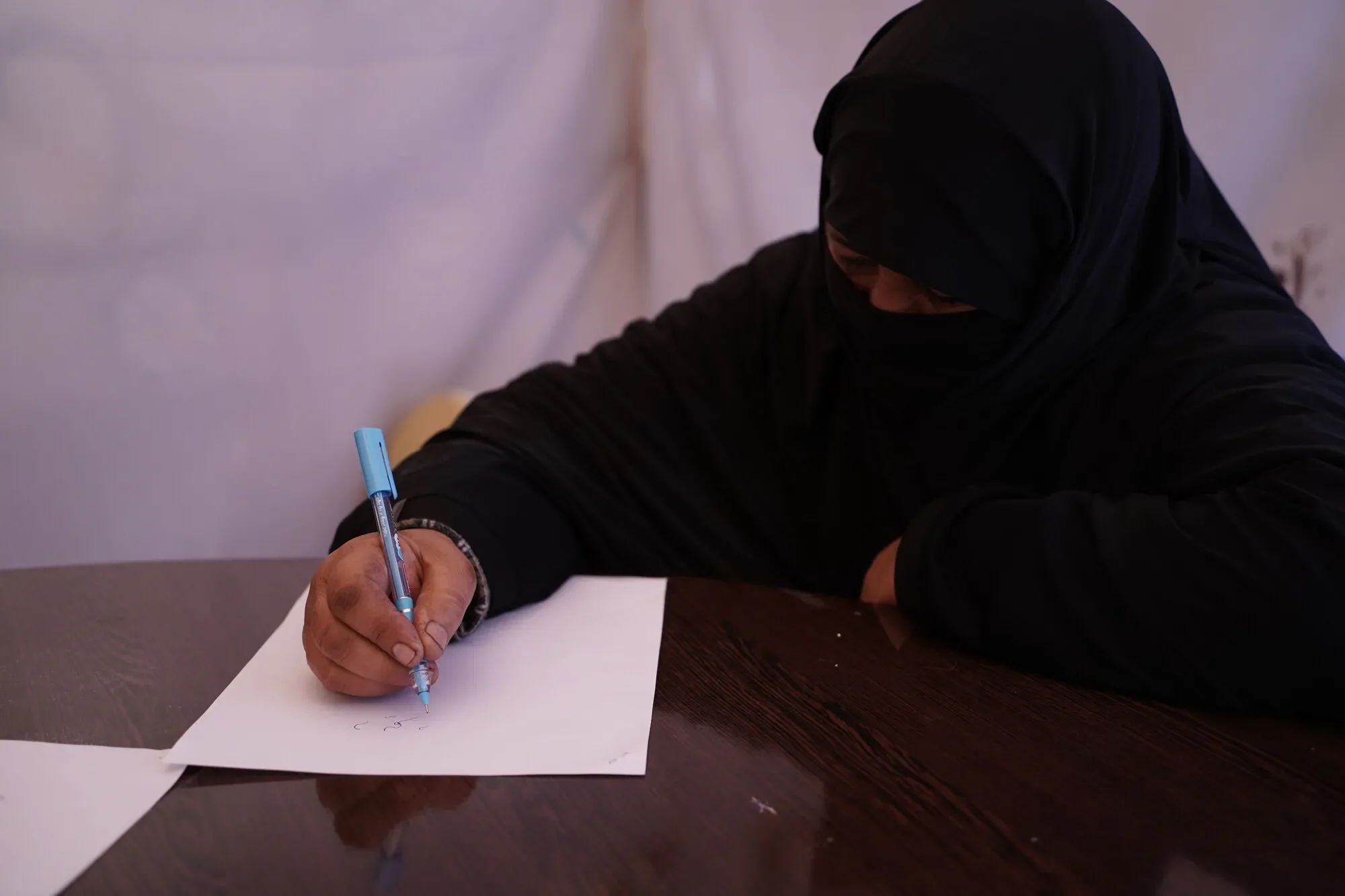 Retrato de Maha escribiendo con un bolígrafo sobre papel