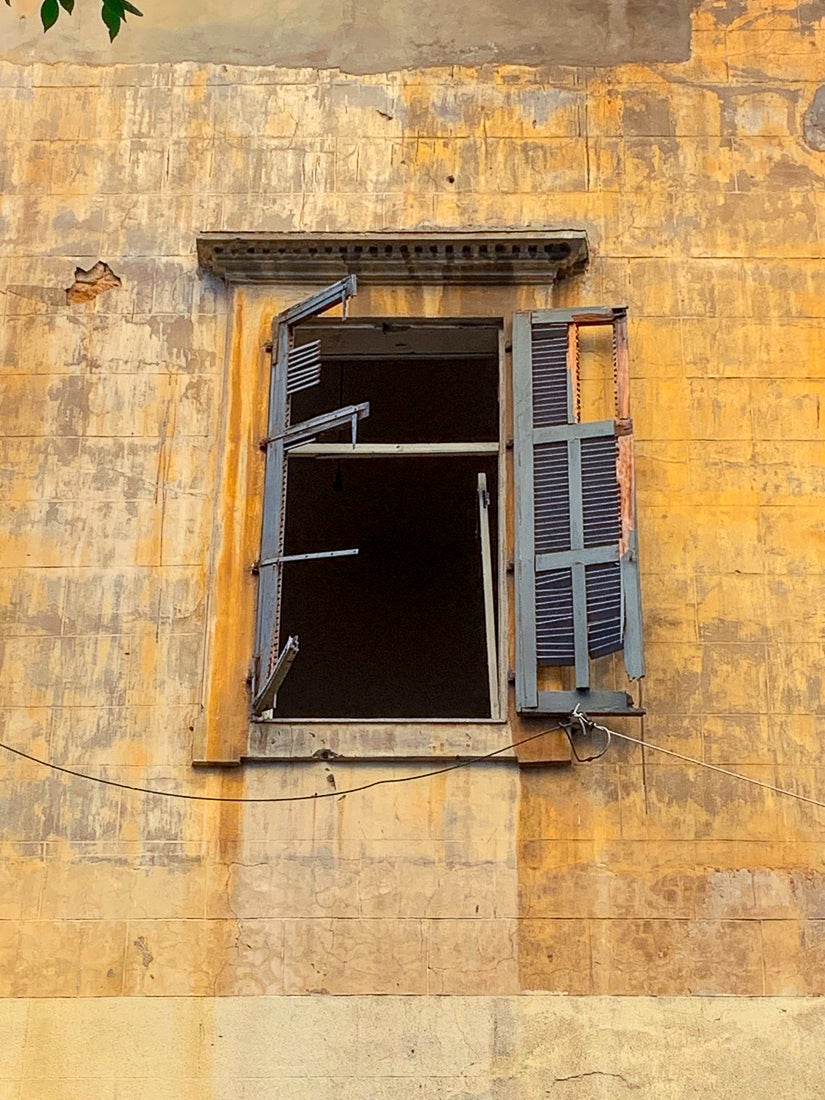 Image d'une fenêtre sans vitre et volets en lambeaux