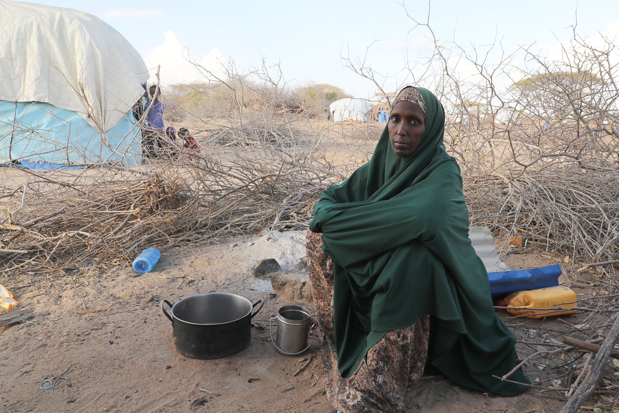 Retrato de mujer somalí al aire libre, con ollas.