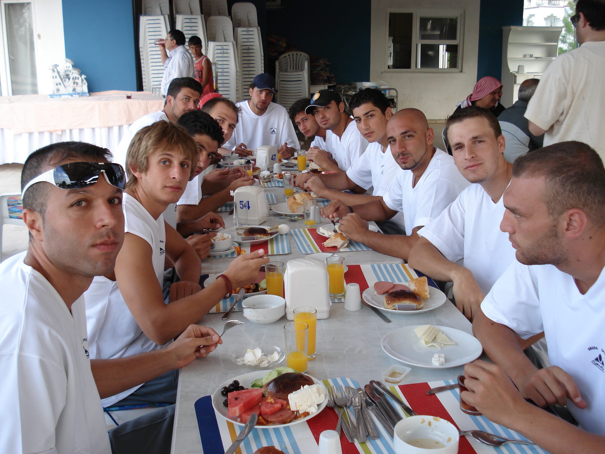 A basketball team, all wearing white, eating a meal together