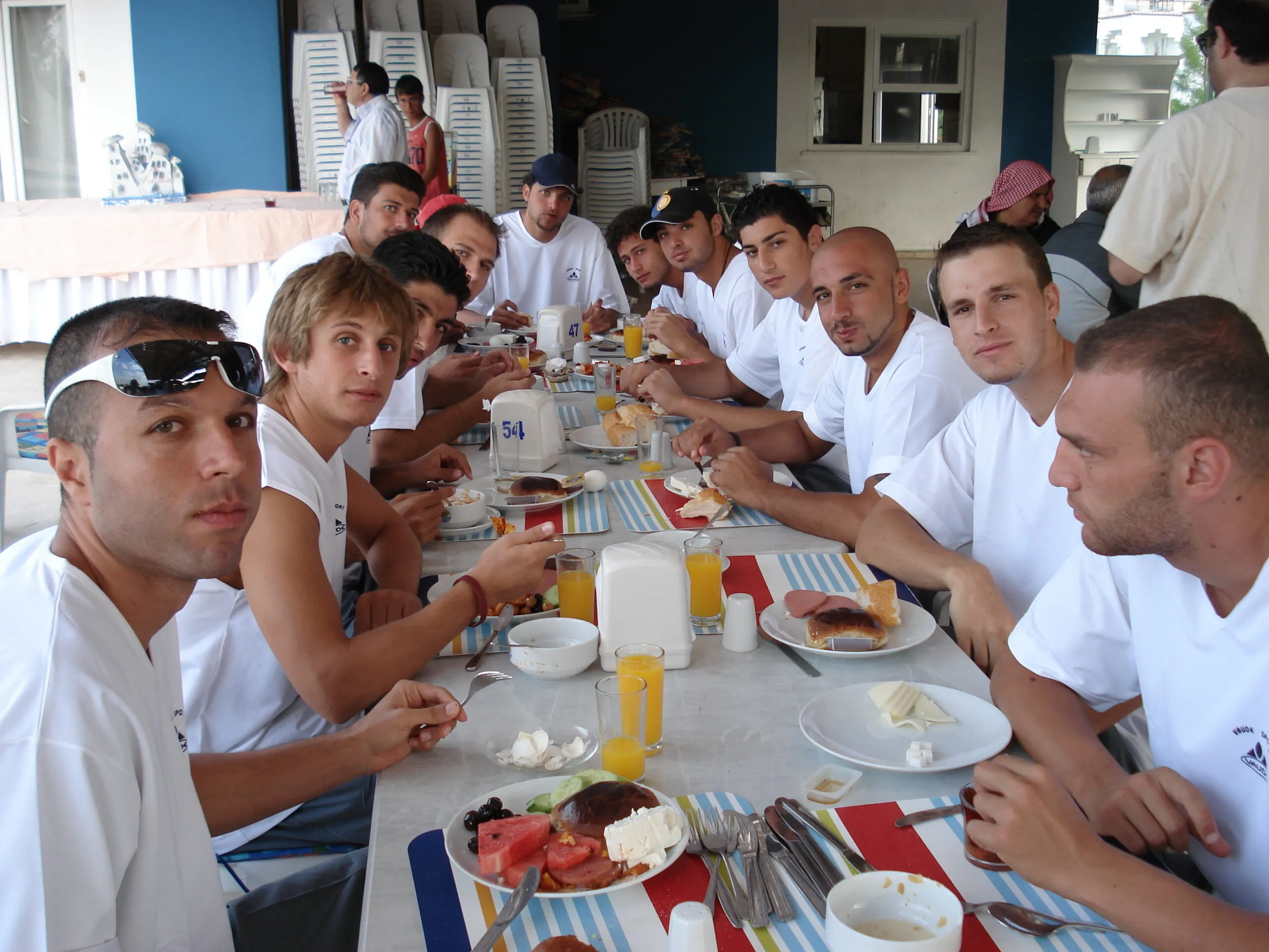 Um time de basquete, todos vestidos de branco, comendo juntos