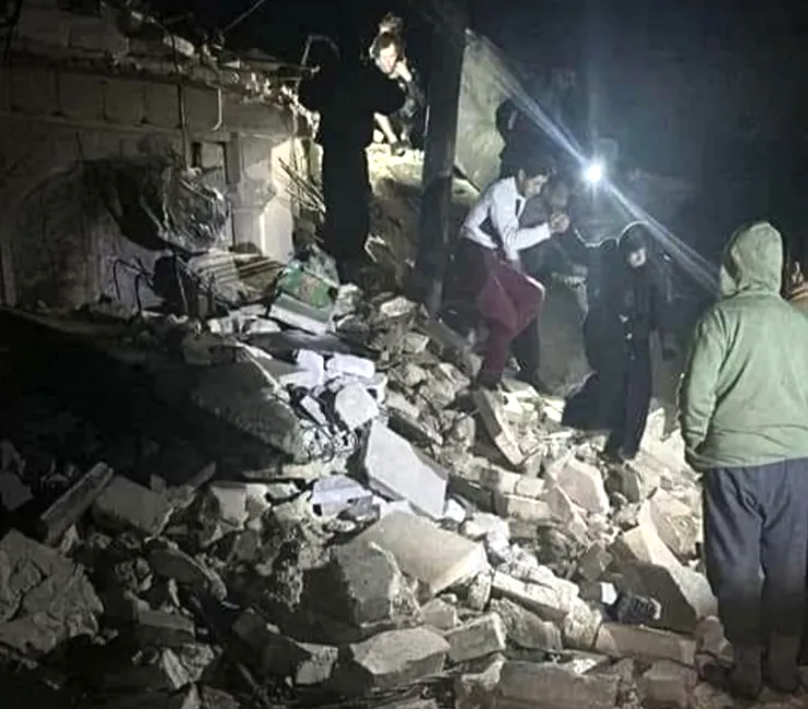 Des gens marchent sur des bâtiments détruits après un tremblement de terre en Turquie.
