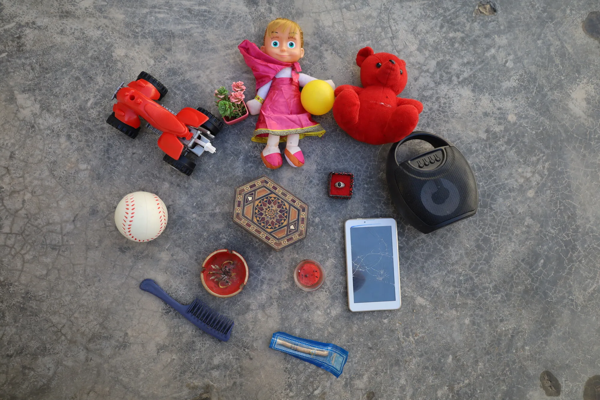An assortment of children's toys, including dolls, a ball, a car, and a comb.