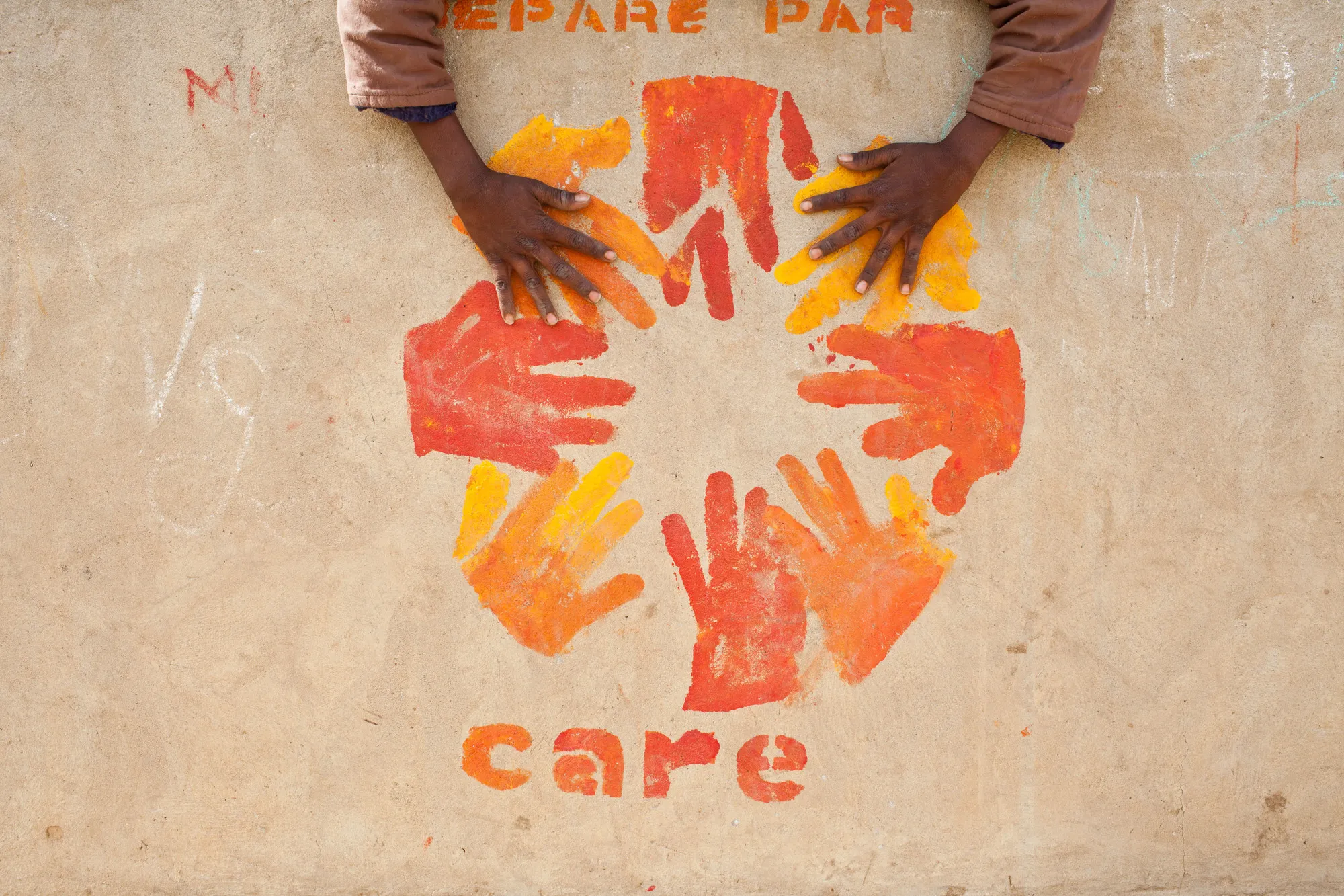 Two hands on a painted CARE logo