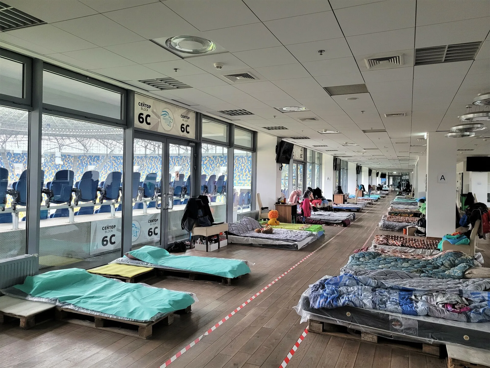 Temporary beds inside a football stadium indoor concourse.