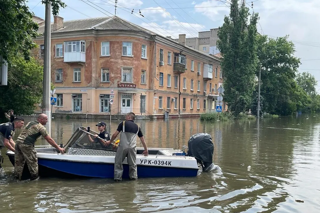 People with a boat in a flooded street.
