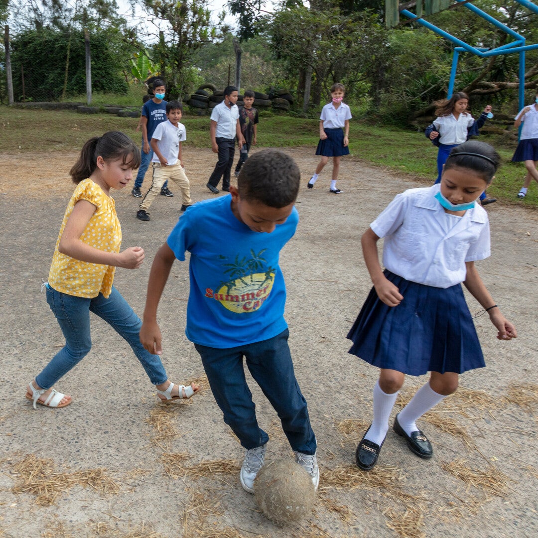 A boy plays informal soccer with two girls