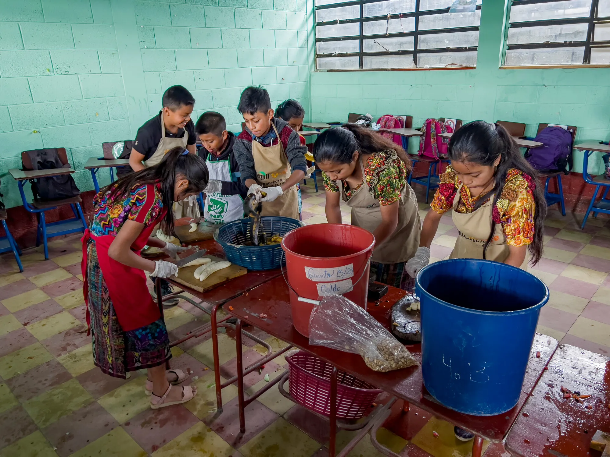 Group of students in a classroom, preparing food.