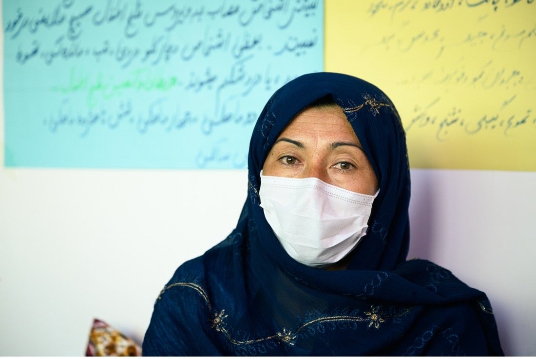 Medium shot of woman with head covering and mask looking at camera