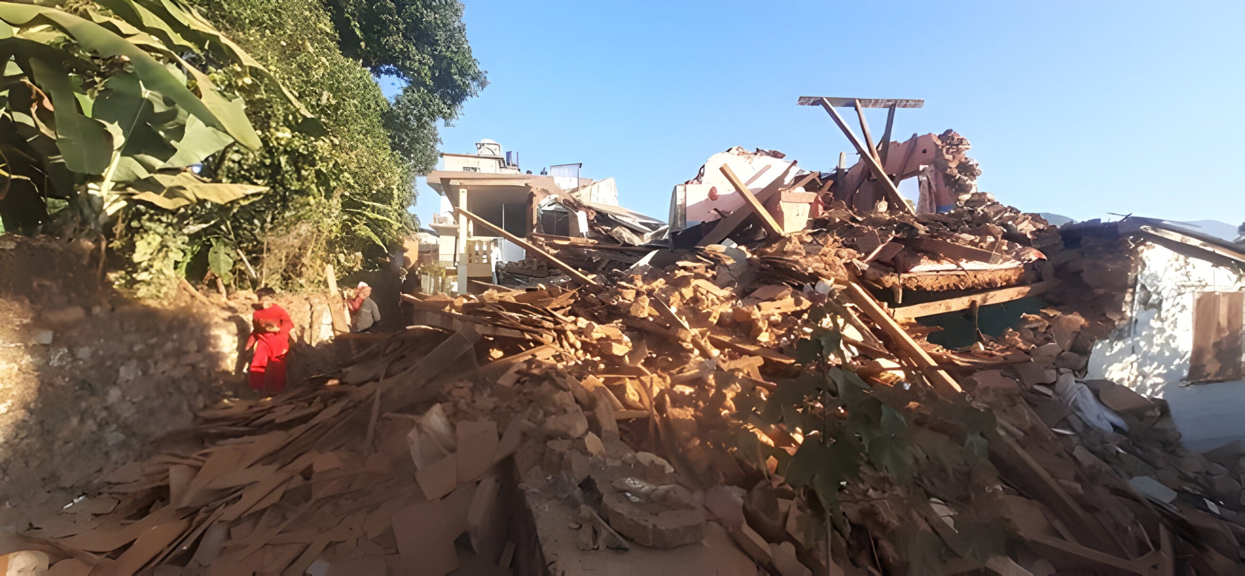 Image of destroyed homes in foreground, blue sky in background