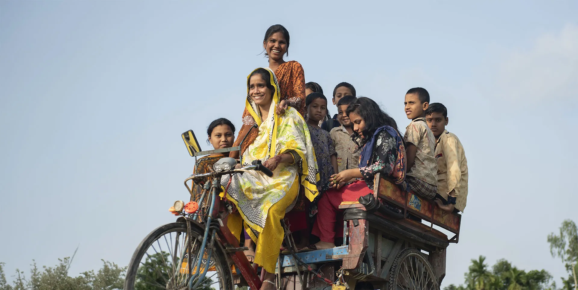 A large group of girls ride together on a bike-drawn cart.