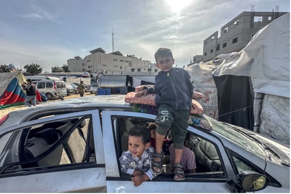 Children playing in and on a damaged car outdoors