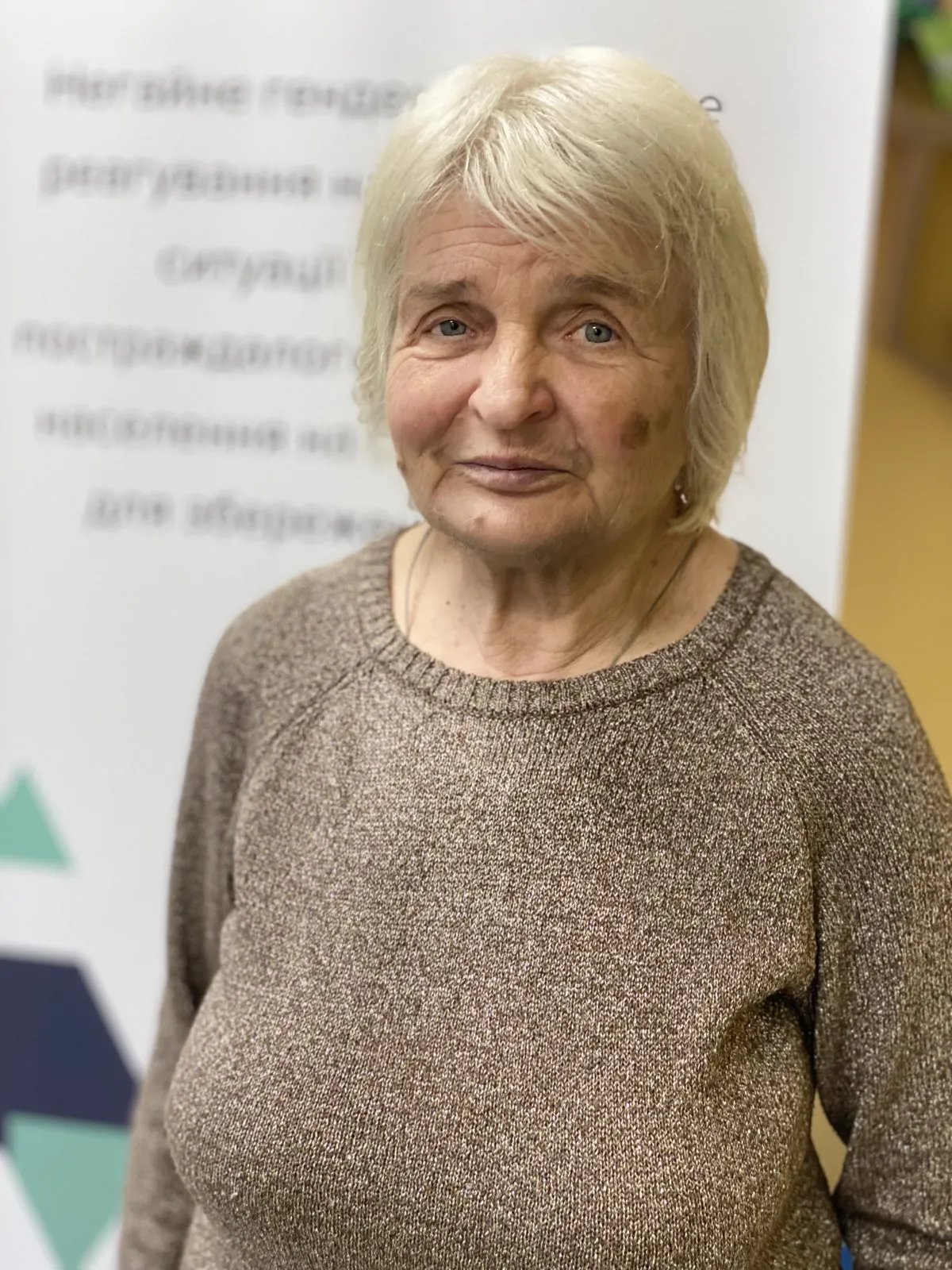 Medium portrait of older woman in brown sweater.