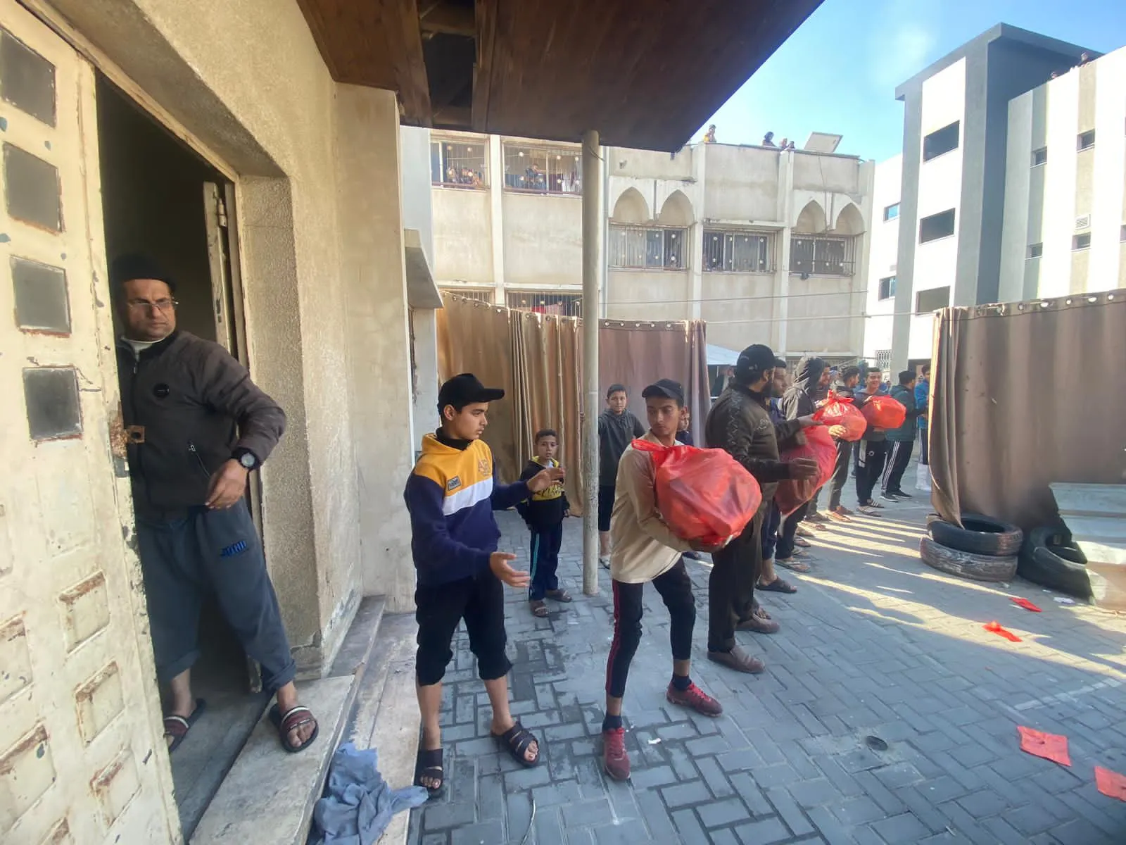 A line of people pass bags of supplies to the door of a building.
