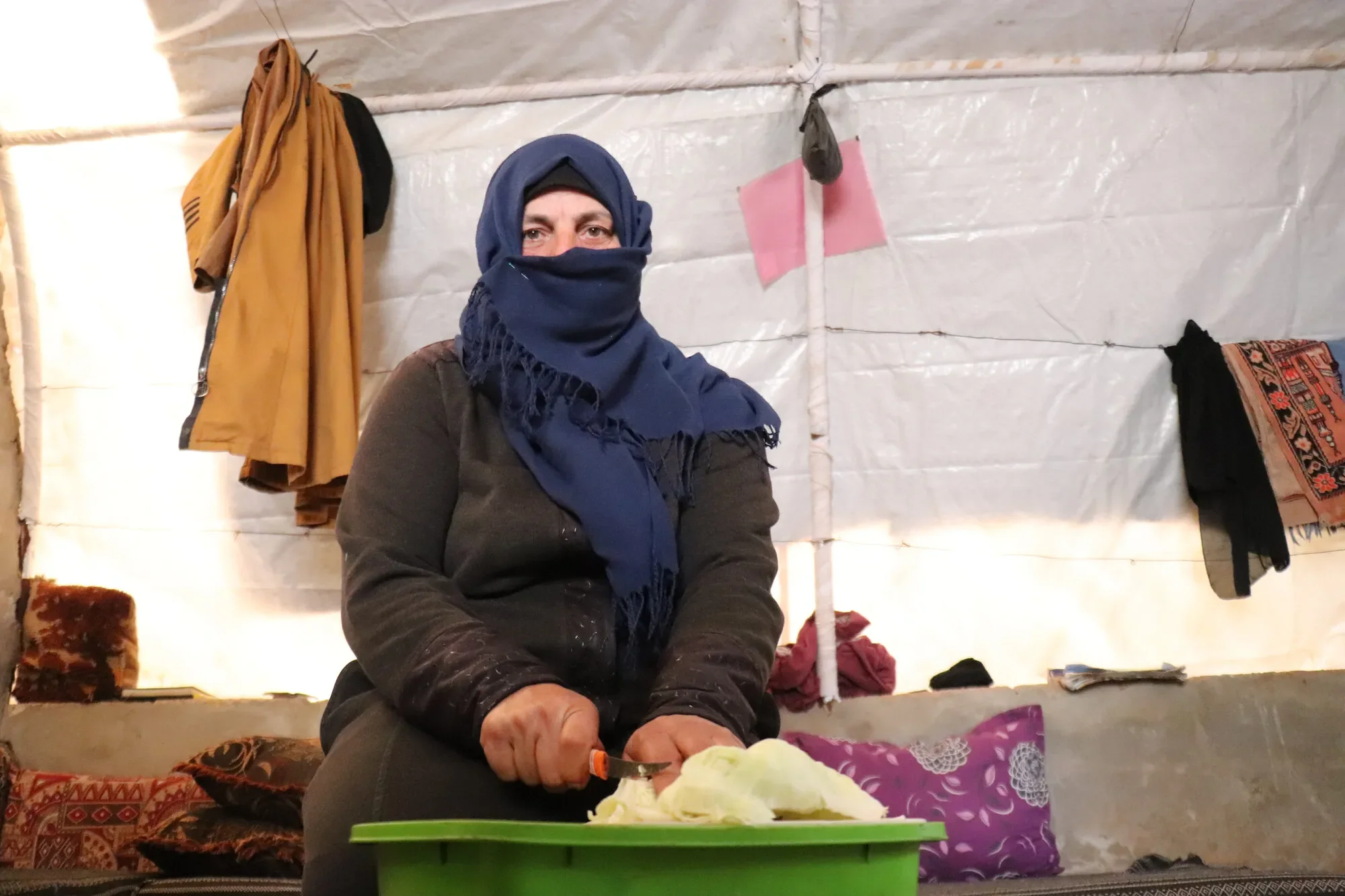 An internally displaced Syrian woman preparing food in her tent.