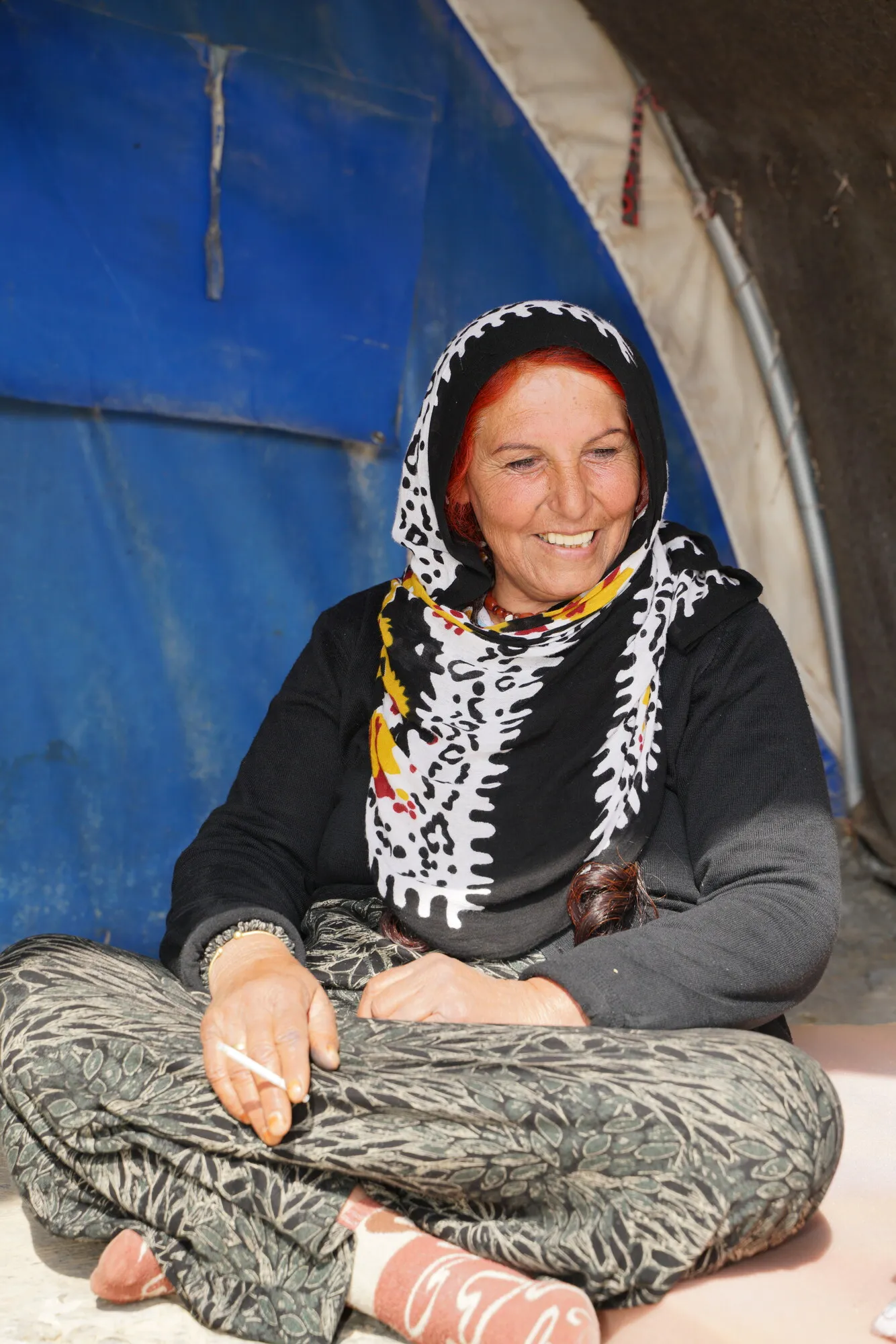 An internally displaced Syrian woman, smiling next to her tent.