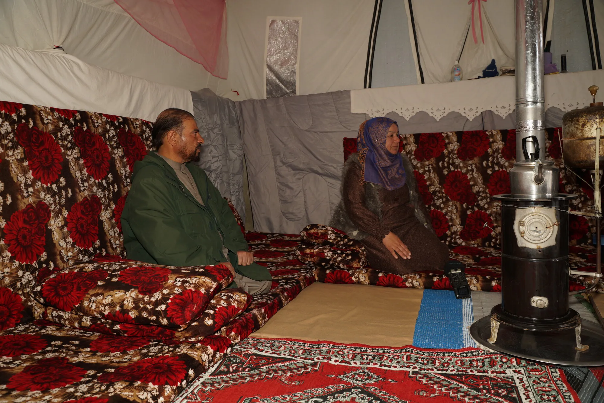 An internally displaced woman and her husband sitting inside their tent.
