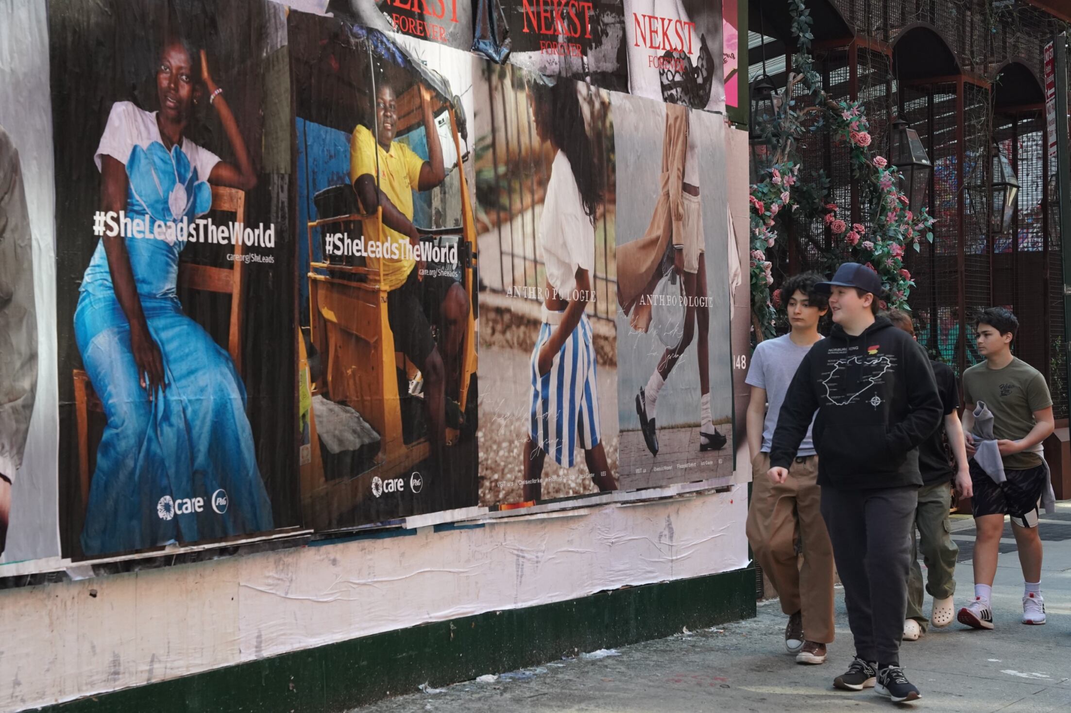 A group of people walk by print ads in New York City showcasing CARE and P&G's International Women's Day campaign.