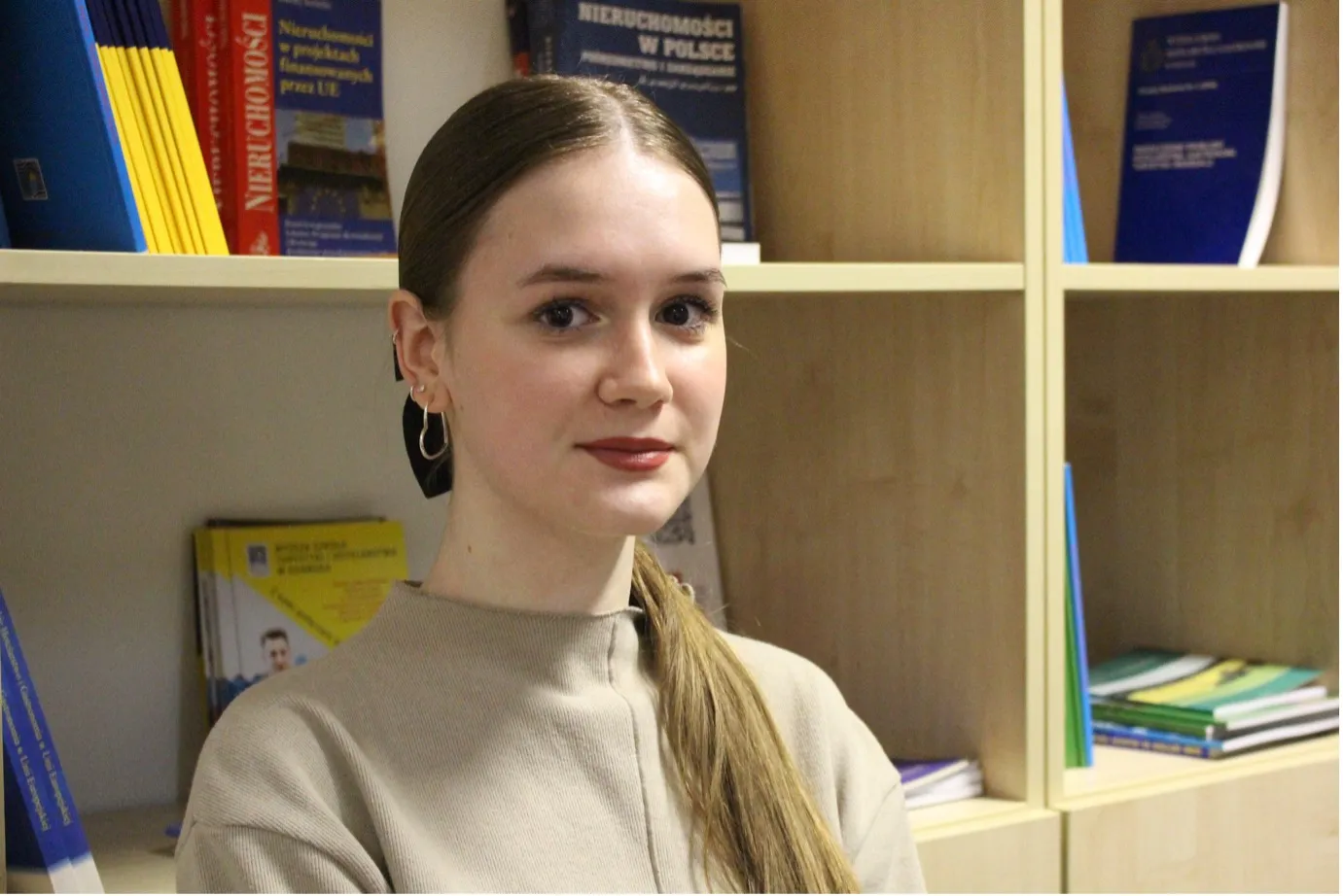 Portrait of a young woman, with bookshelves in the background.