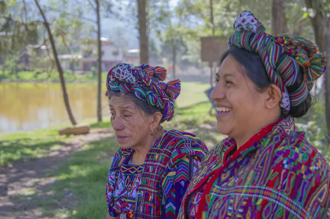 Two Guatemalan women, one middle-aged and one elderly, stand together and smile.