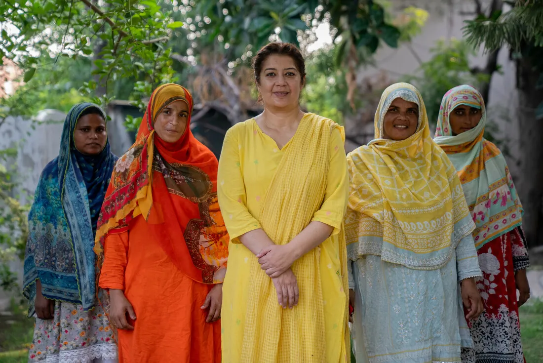 Four women stand together confidently, each wearing bold colors.