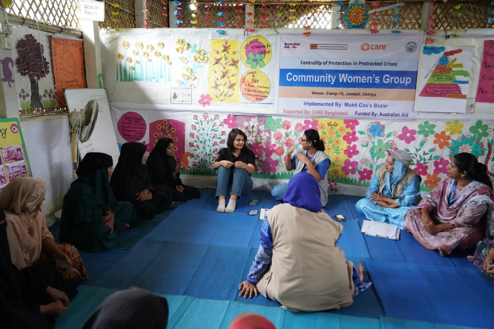 A group of women sitting in a circle indoors, engaged in conversation and attentive listening.