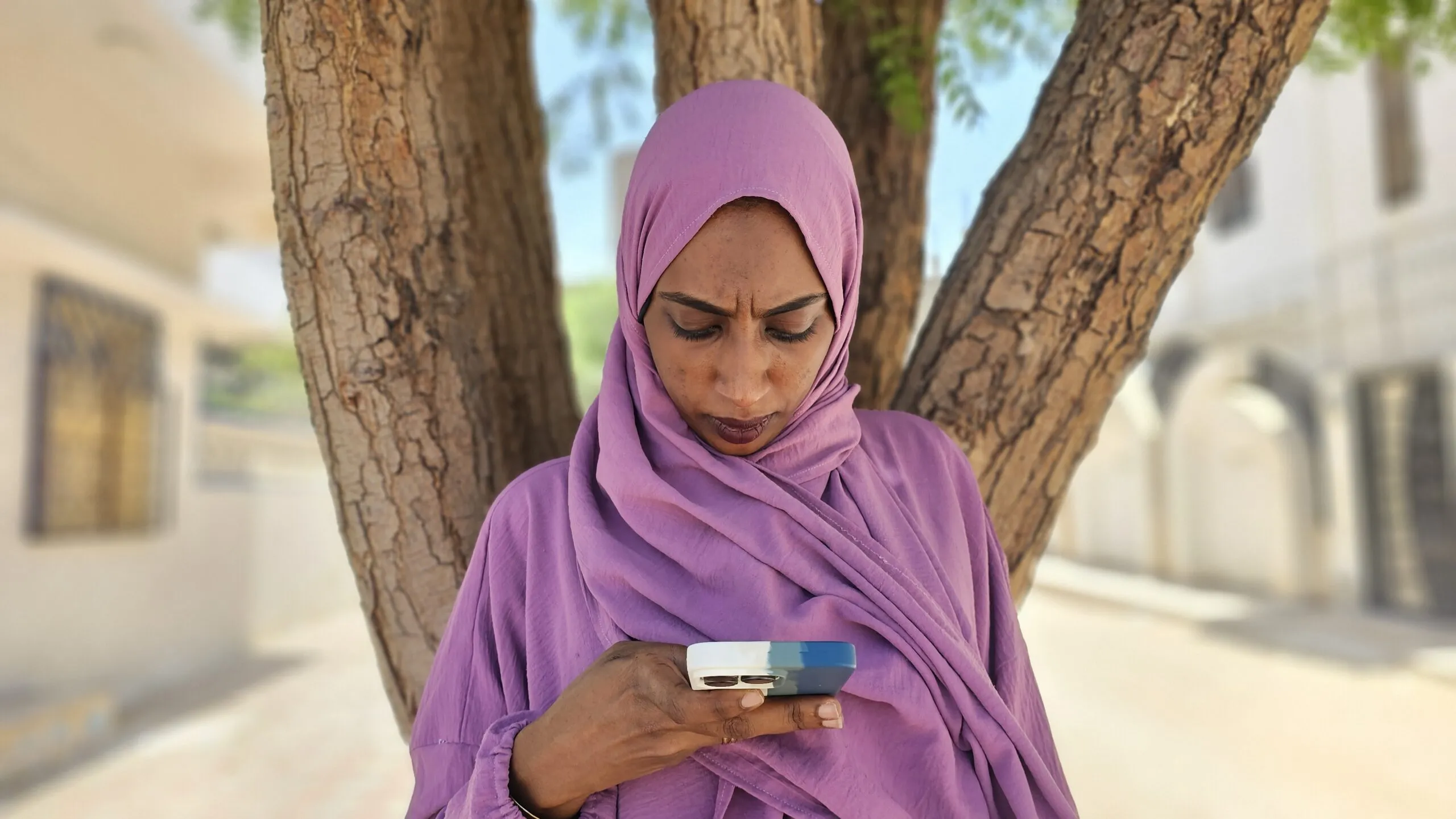 A humanitarian in a pink headscarf texts on her phone.