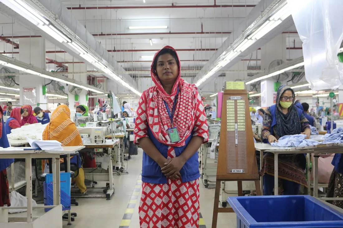 A Bangladeshi woman stands amid workers at a garment factory.