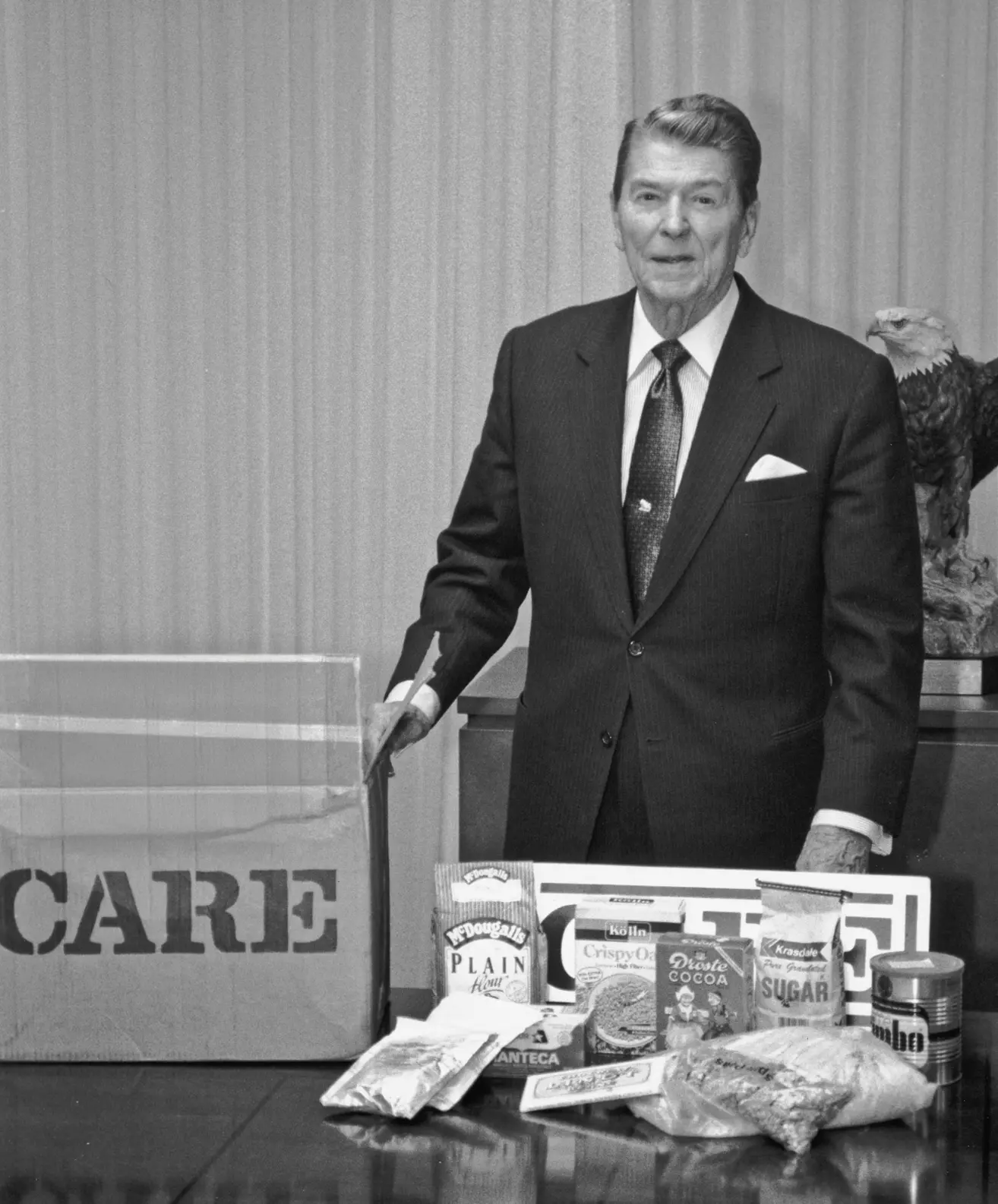 President Ronald Reagan stands next to an original CARE PACKAGE with rationed goods.