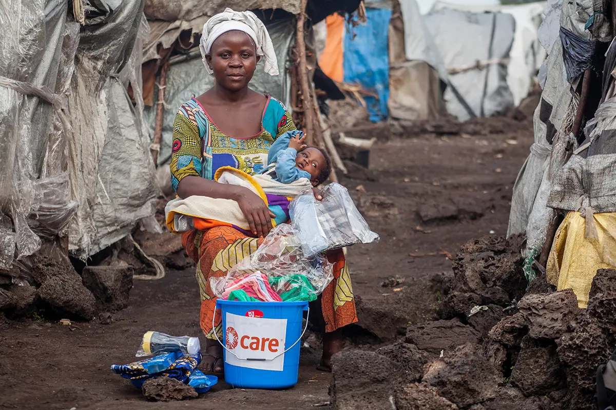 Woman sits outdoors holding an infant.