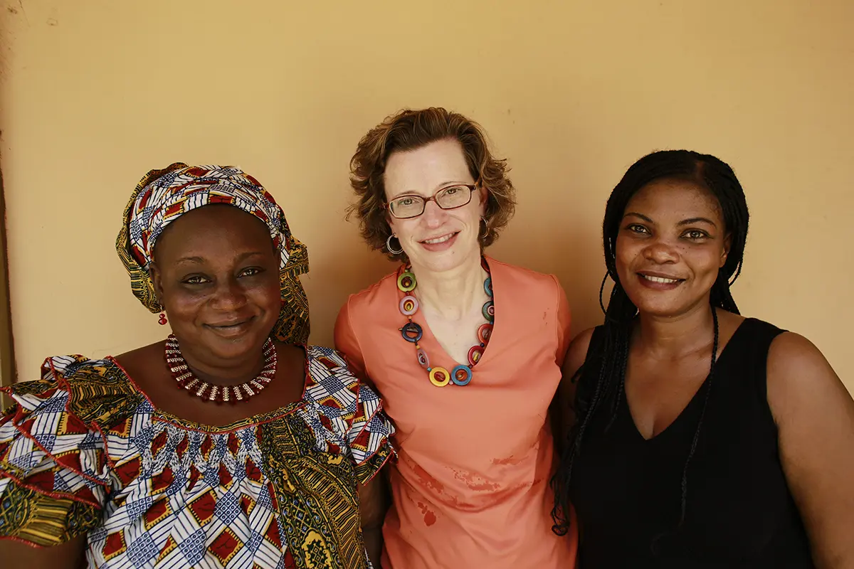 CARE President and CEO Michelle Nunn stands and smiles with two women.