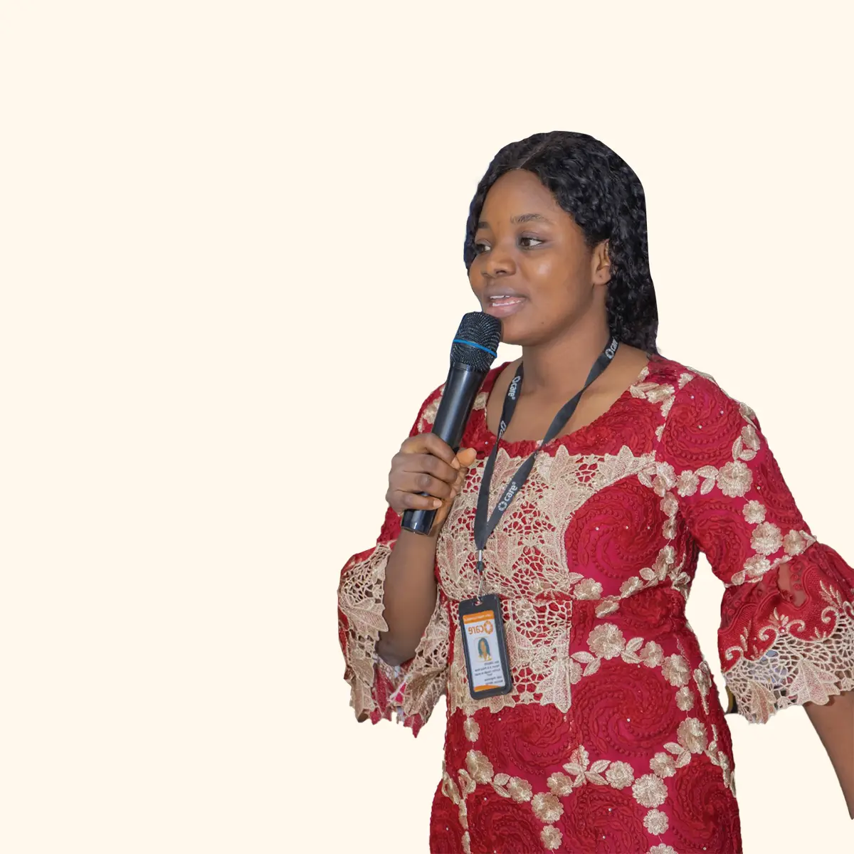 A woman wearing a bright red patterned dress speaks into a microphone.
