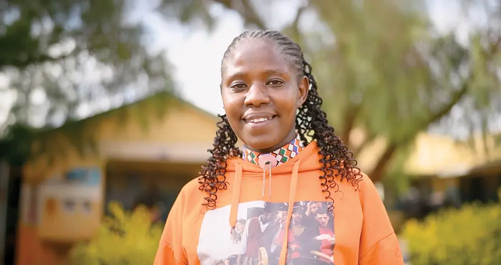 A Black woman wearing an orange hoodie sweatshirt smiles.