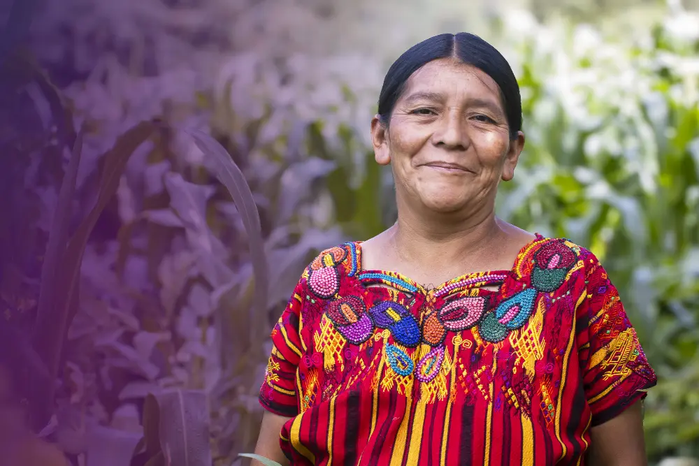A portrait of a woman standing in front of a field of crops.