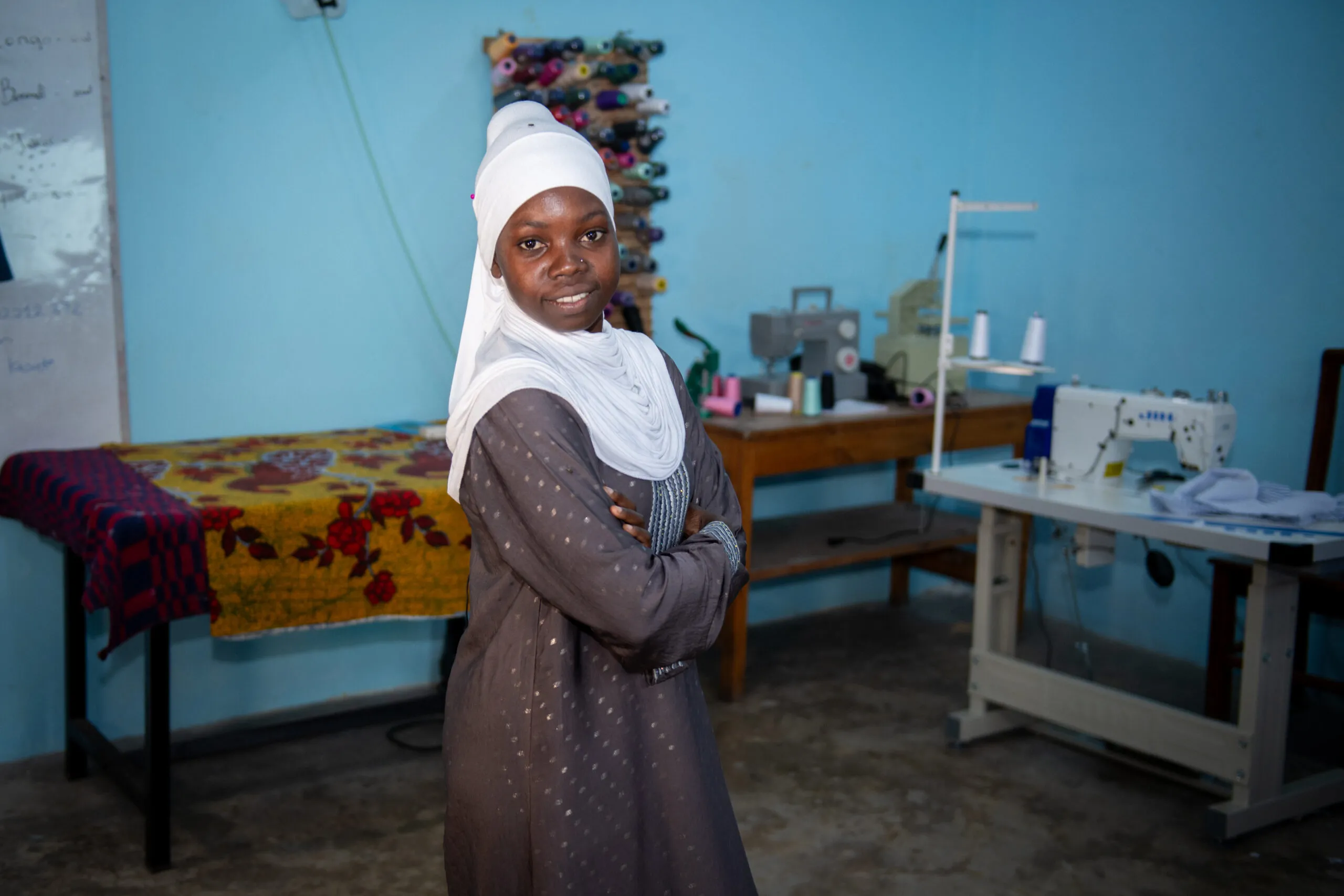 A young Tanzanian woman in a white headscarf looks into the camera.
