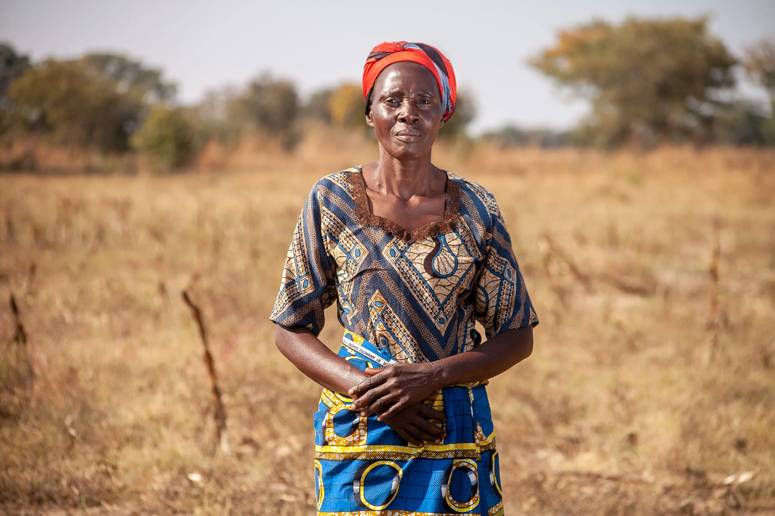 A Zambian woman farmer gazes directly at the camera with a confident expression.